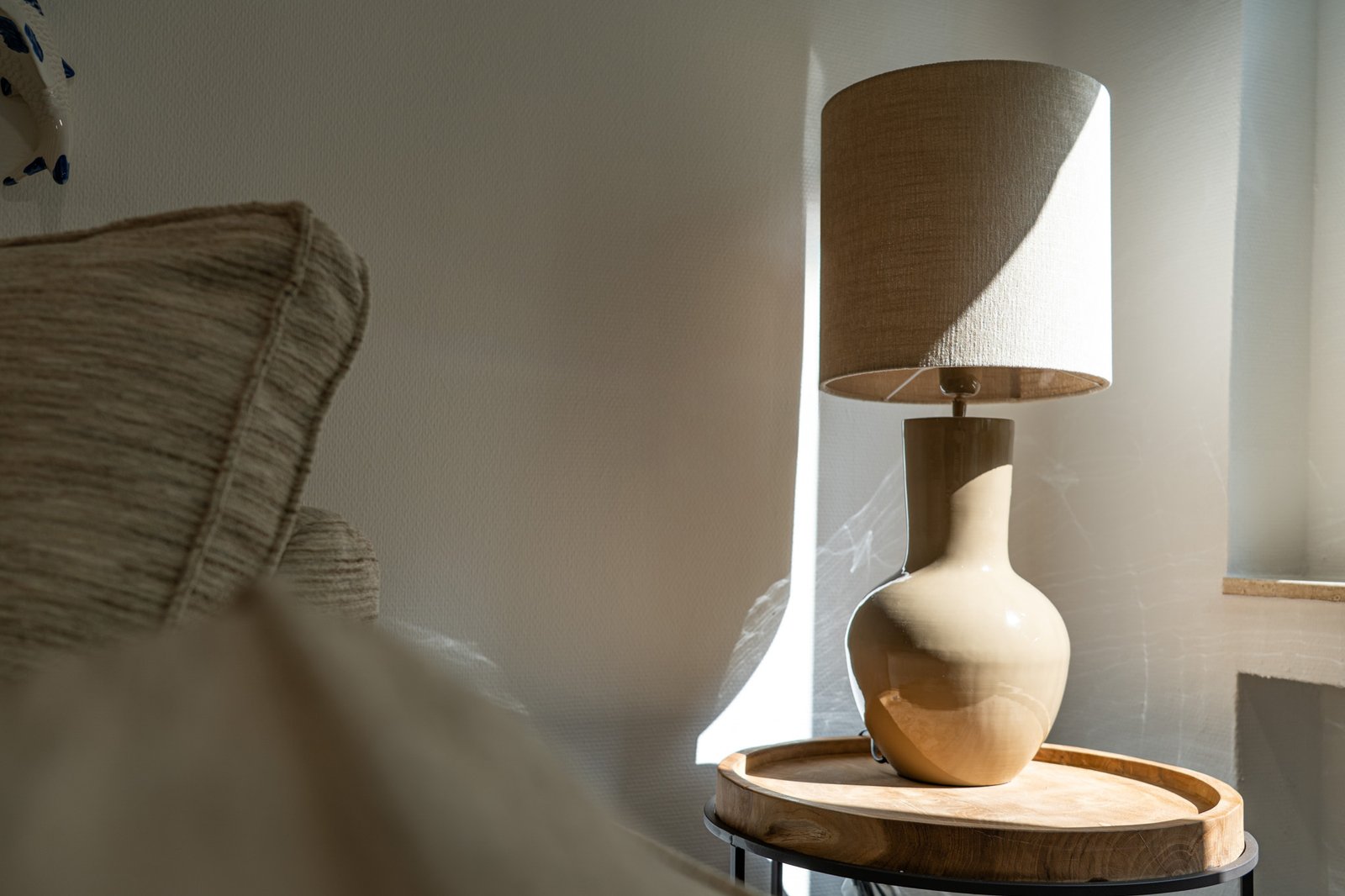 Ruhige, minimalistische Szene mit Tischlampe auf Holztisch, Sofa im Vordergrund, warme Beleuchtung.