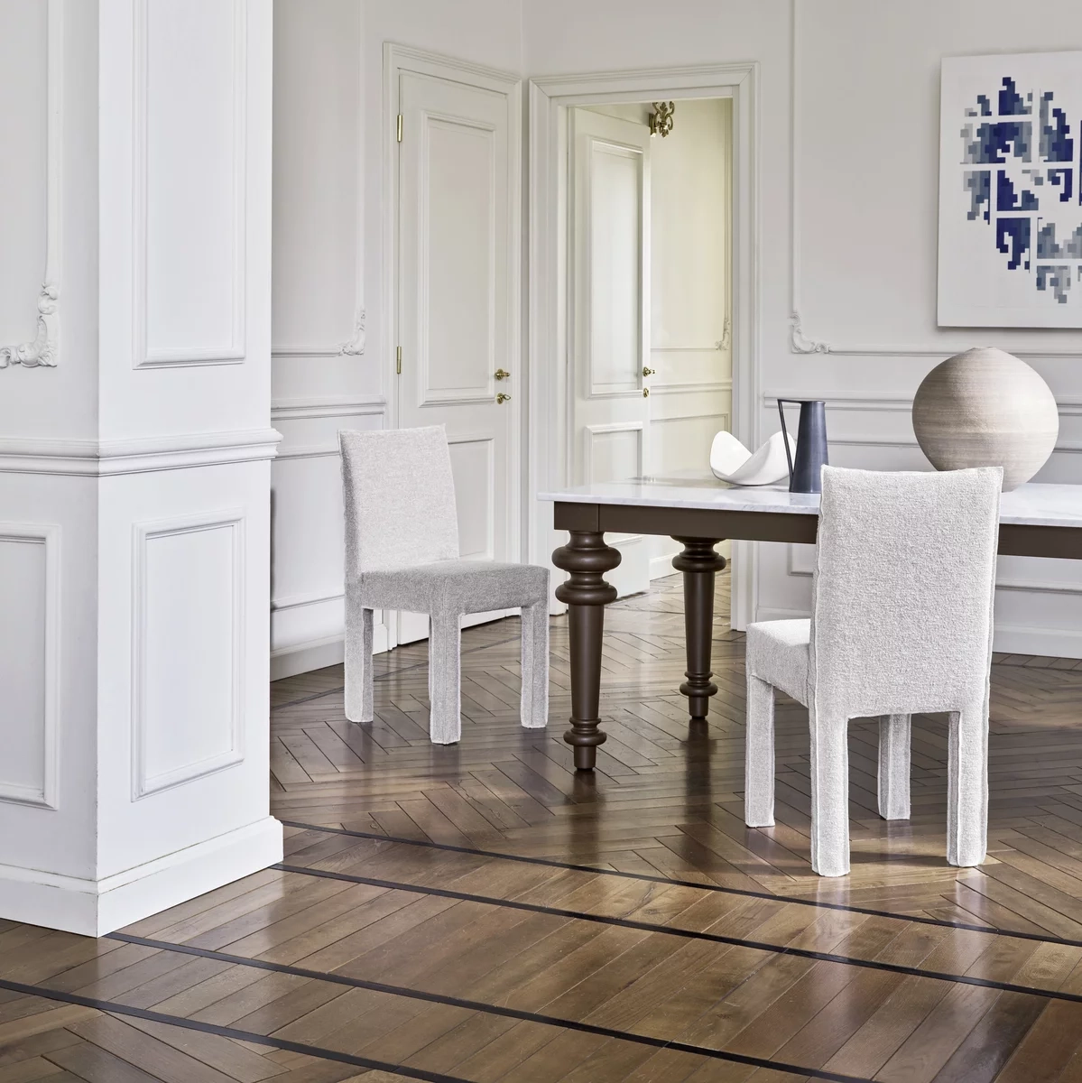 Elegantes Esszimmer mit hellen Stühlen, dunklem Holztisch und dekorativer Vase auf Fischgrätboden.