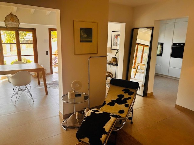 Modernes Wohnzimmer mit Kuhfell-Liege, Beistelltisch, Esstisch und großem Spiegel, warm und einladend.