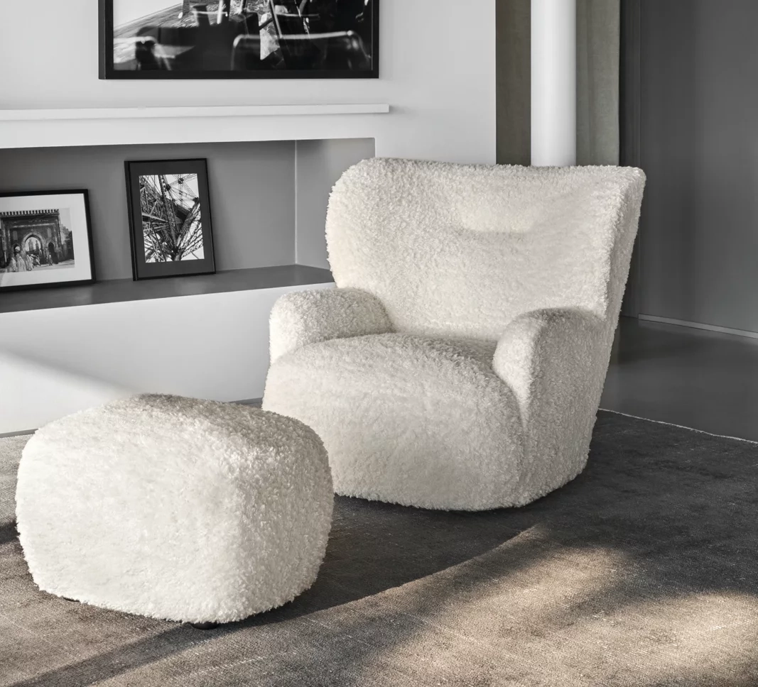 Gemütliches Wohnzimmer mit weißem Sessel und Hocker, umgeben von Schwarz-Weiß-Fotografien.